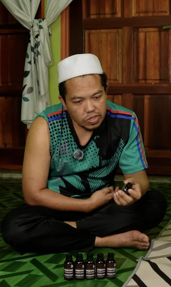 Pelanggan memegang botol Minyak Urut Pusaka Ayah Mat