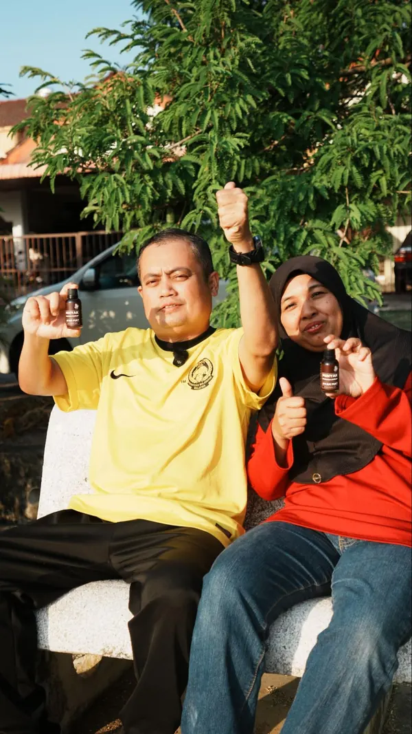 Pasangan pelanggan menunjukkan botol Minyak Urut Pusaka Ayah Mat