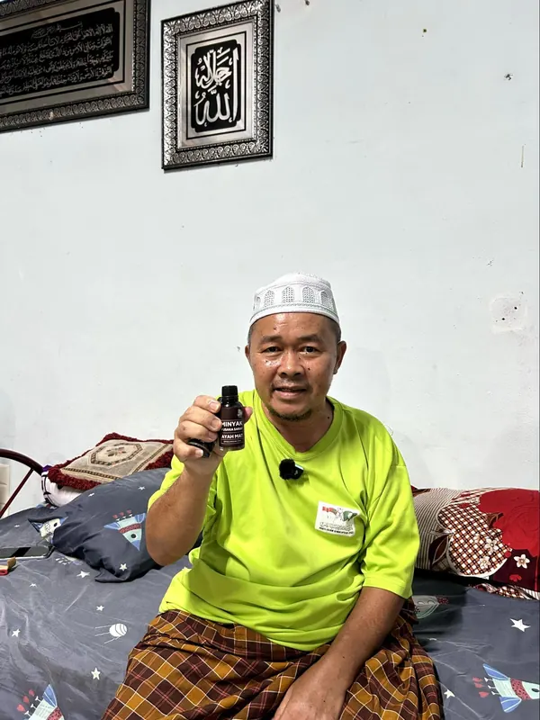 Pelanggan memegang botol Minyak Urut Pusaka Ayah Mat