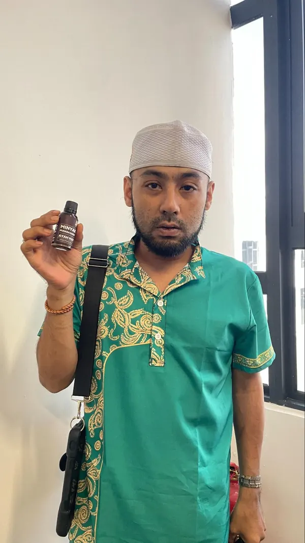 Pelanggan memegang botol Minyak Urut Pusaka Ayah Mat